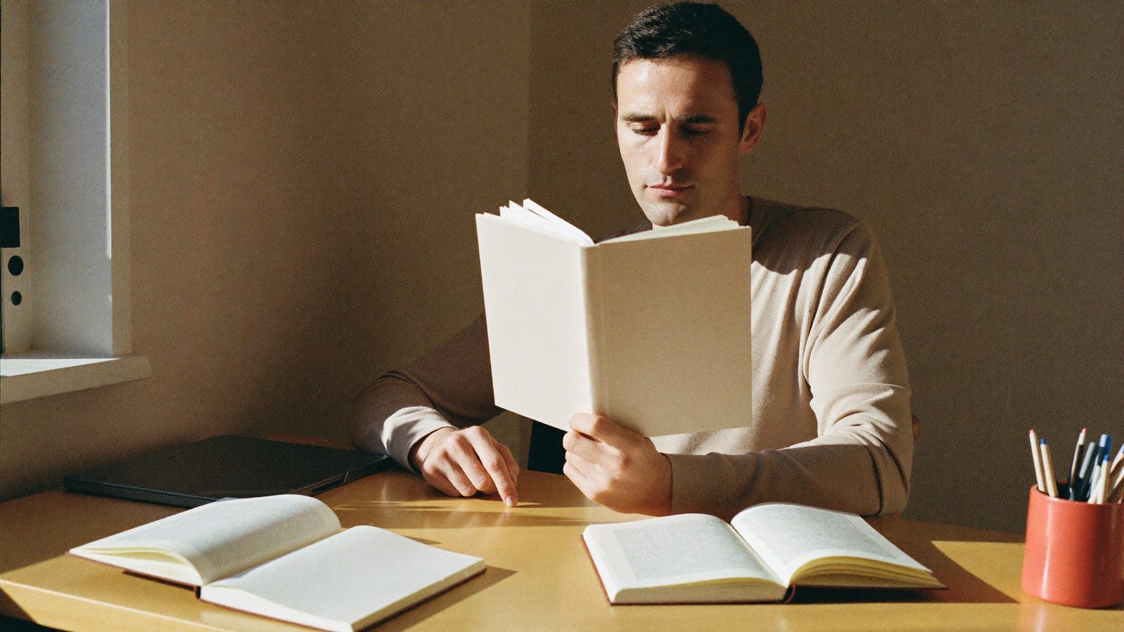 Un adulto studia a casa un libro di un nuovo indirizzo, per prendere un secondo diploma.