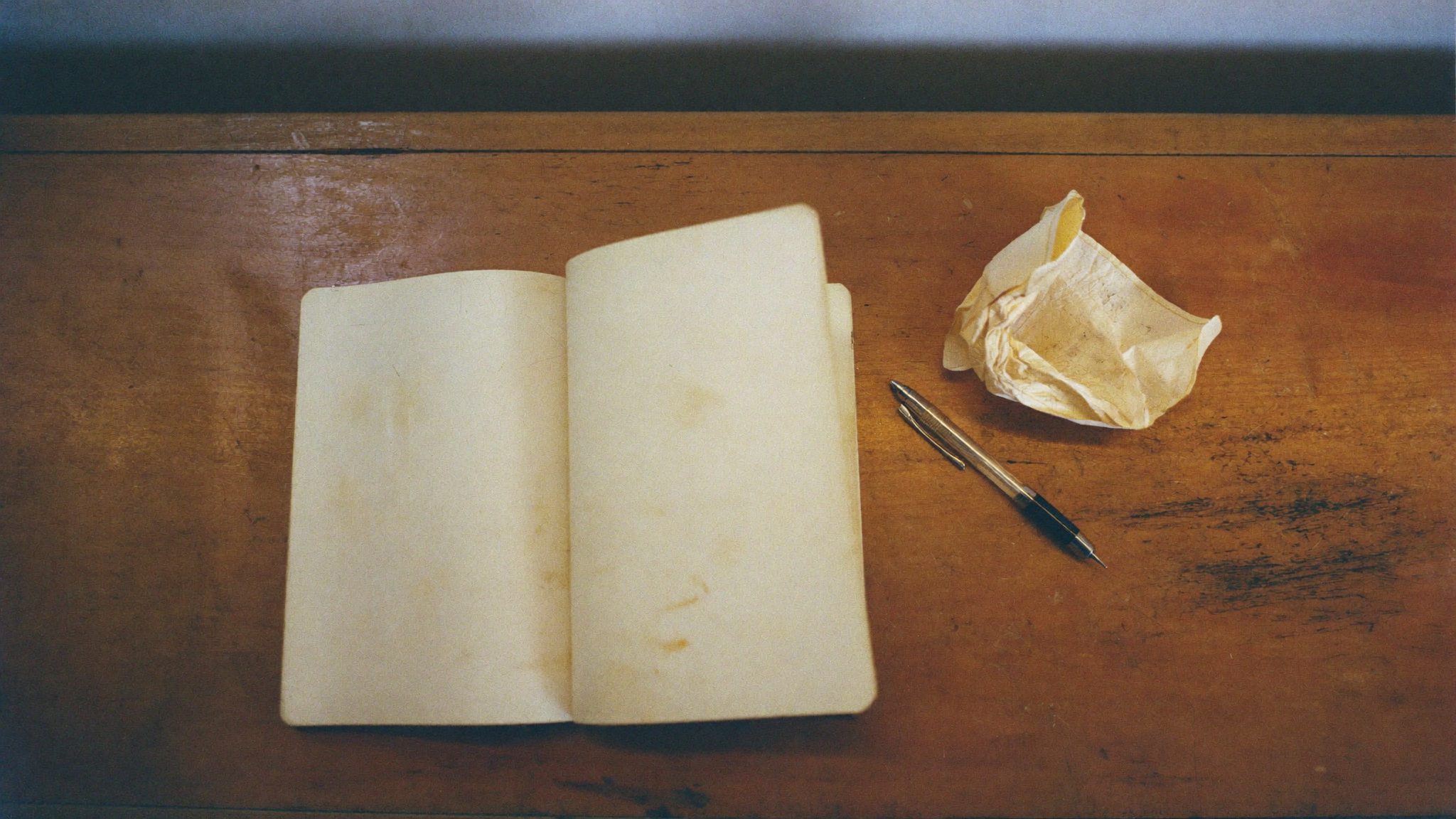 Persona che studia da sola di sera, libri aperti sul tavolo, luce calda
